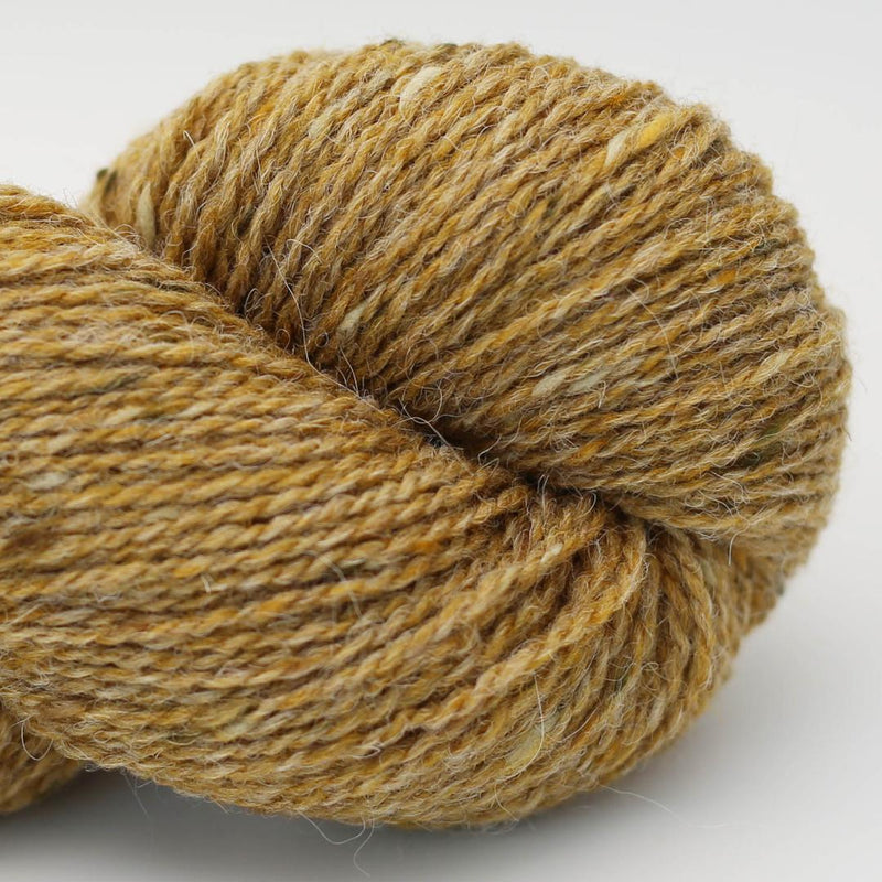 Close-up of a skein of gold yarn with deep gold and pale speckles Beara Irish wool and UK alpaca tweed dk, worsted or aran weight yarn by Hey Mama Wolf 