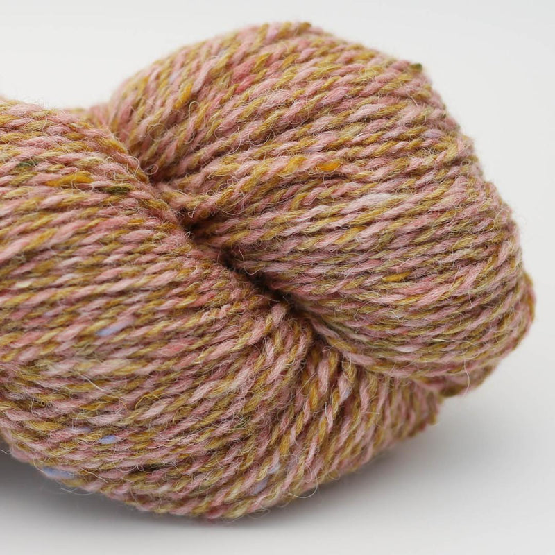 Close-up of a skein of pink and gold marled yarn Beara Irish wool and UK alpaca tweed dk, worsted or aran weight yarn by Hey Mama Wolf 